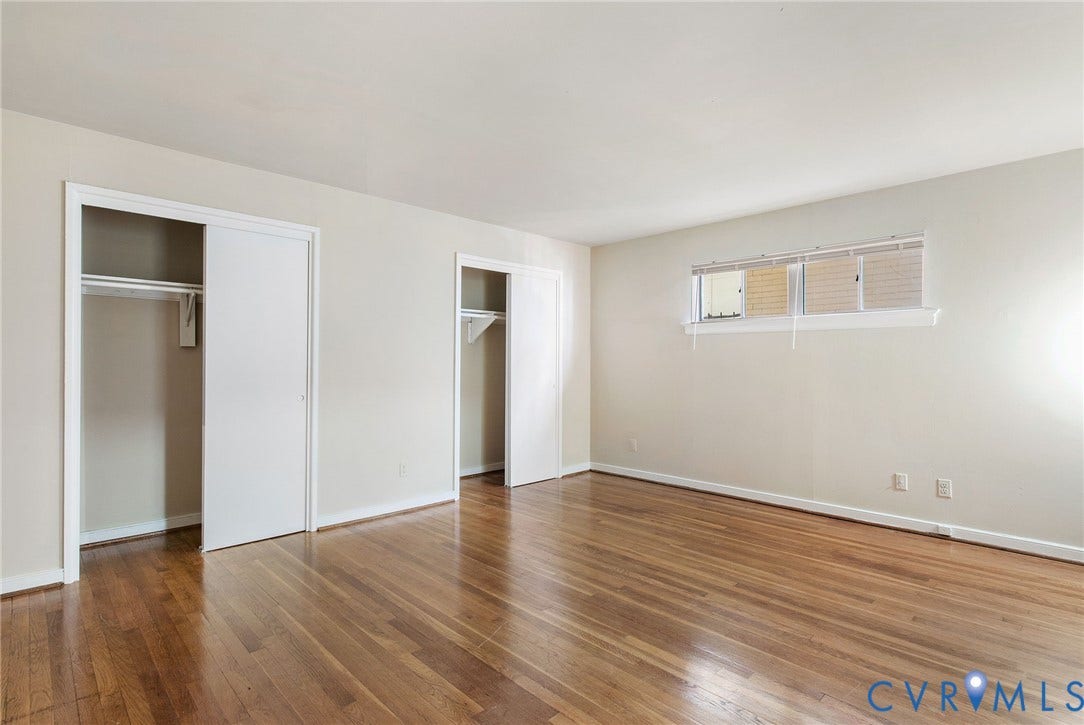 Hardwood flooring, twin sliding door closets with built-in shelving and hanging rods, and a multi-pane window