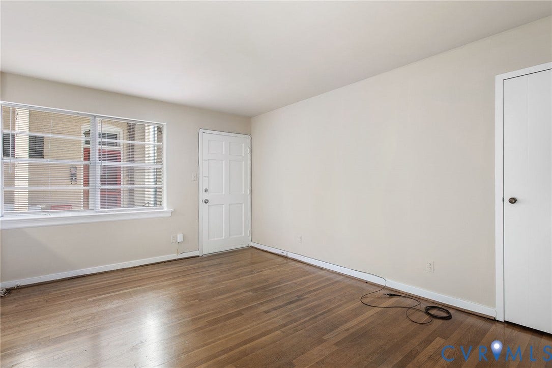 Hardwood flooring, painted walls, white trim, paneled door, and a multi-pane window