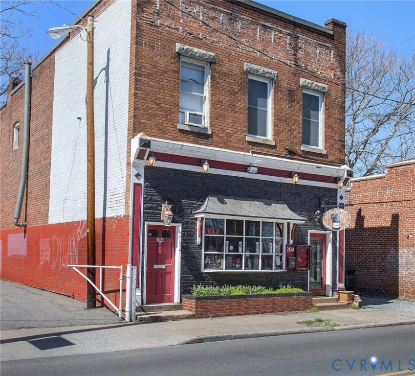 Brick facade with decorative lintels, ground-level commercial entrance, large display window, street-facing pedestrian access, and multiple upper-level windows