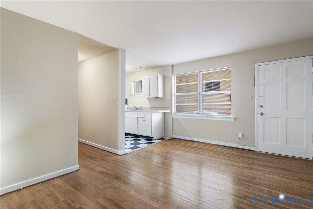 Hardwood-finish flooring, white panel door, double-pane window, white kitchen cabinetry, and checkerboard floor tiling