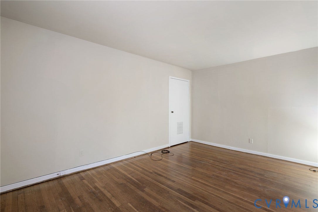 Wood-finish flooring with light-toned walls and a white door