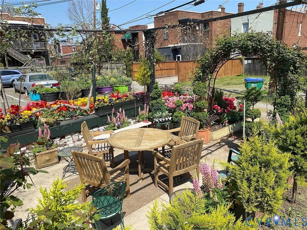 Patio area featuring a curved arbor, mature plantings, and a stone paver surface