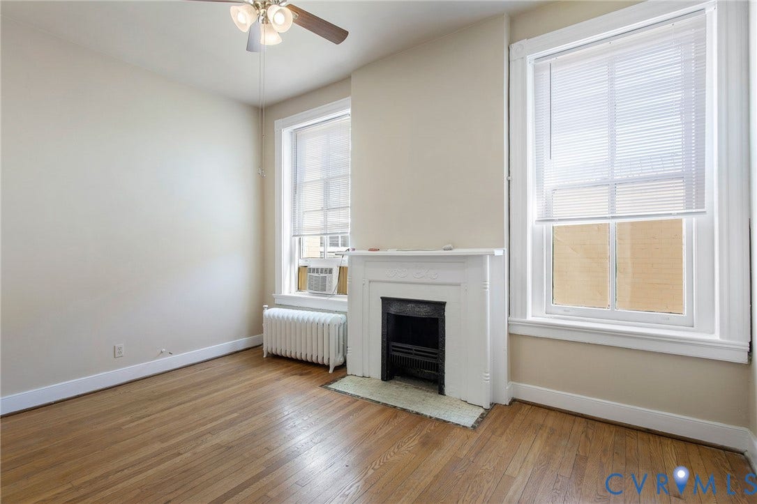 2604 Grove, #5, Richmond, VA 23220 Hardwood flooring, decorative fireplace, two large windows, white window blinds, and a ceiling fan with integrated lighting