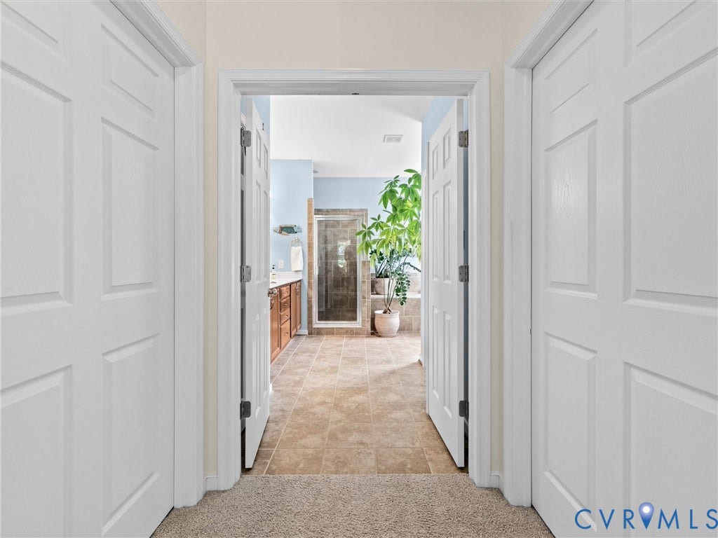 1663 Centerville Parke Lane, The Parke At Centerville, Manakin Sabot, VA 23103 Carpeted hallway with panel doors opening to a bathroom featuring a tile floor, wood-finish vanity, and glass-enclosed shower