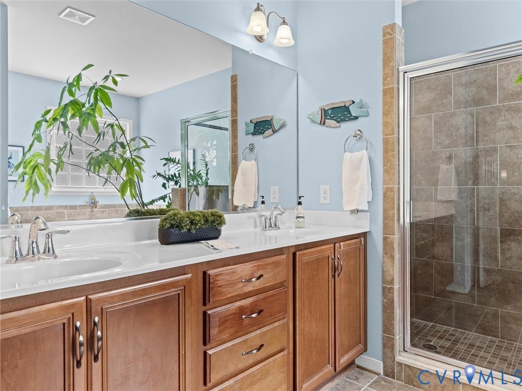 1663 Centerville Parke Lane, The Parke At Centerville, Manakin Sabot, VA 23103 Double vanity with undermount sinks and wood cabinetry, large mirror, tile flooring, and glass-enclosed shower with tile surround