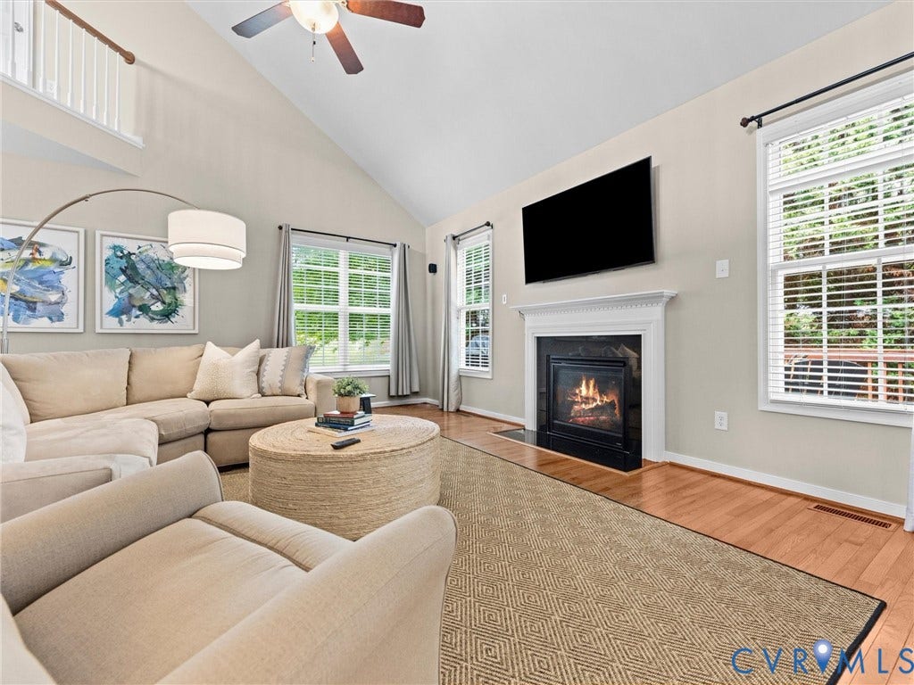1663 Centerville Parke Lane, The Parke At Centerville, Manakin Sabot, VA 23103 Vaulted ceiling, hardwood flooring, fireplace with white mantel, two large windows, and a ceiling fan