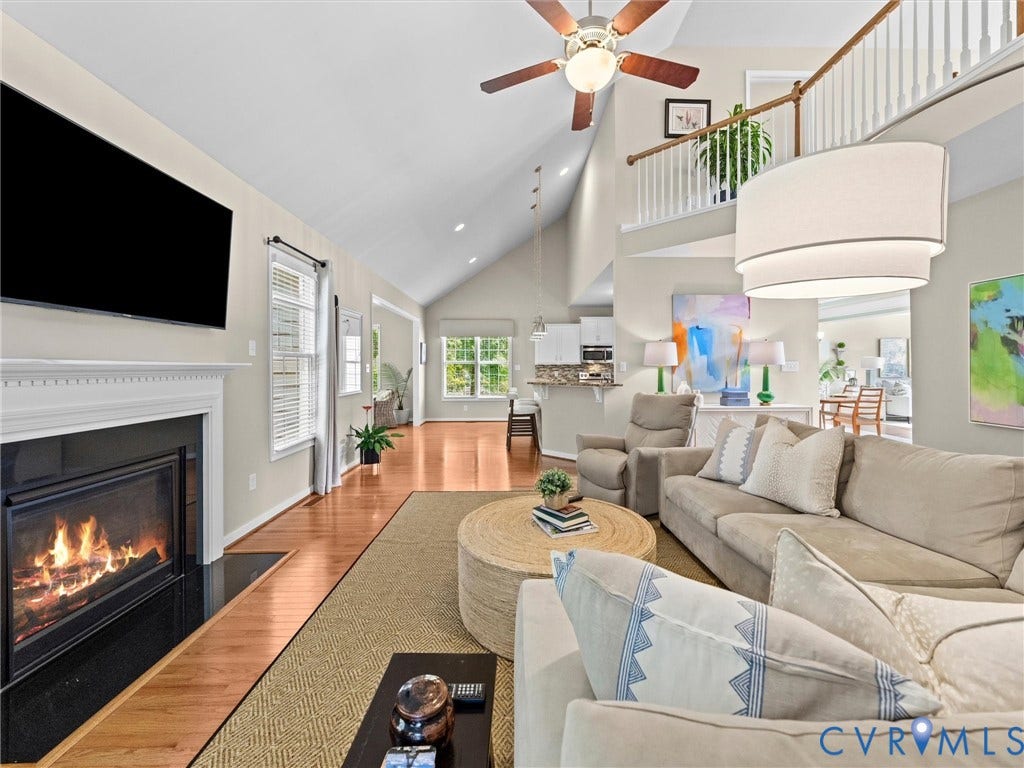 1663 Centerville Parke Lane, The Parke At Centerville, Manakin Sabot, VA 23103 Vaulted ceiling with ceiling fan, wood-finish flooring, white mantel fireplace with black surround, white staircase with wood handrail, and an upper-level balcony