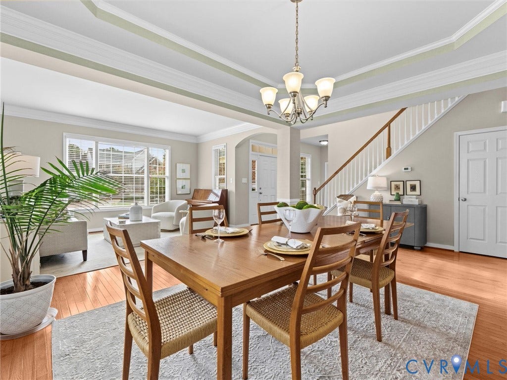 1663 Centerville Parke Lane, The Parke At Centerville, Manakin Sabot, VA 23103 Tray ceiling with crown molding, chandelier lighting, wood-finish flooring, staircase with white spindles, and expansive windows