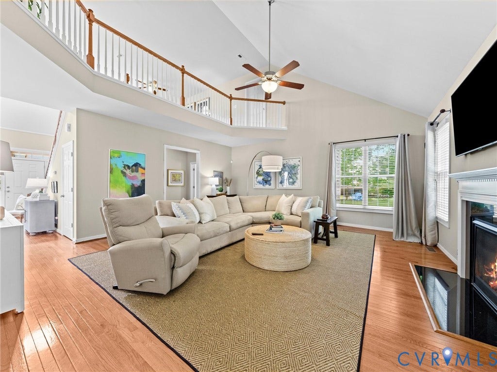 1663 Centerville Parke Lane, The Parke At Centerville, Manakin Sabot, VA 23103 Vaulted ceiling with a ceiling fan, wood-finish flooring, two-story living area, fireplace with a white mantel, and an upper-level railing overlooking the main living space