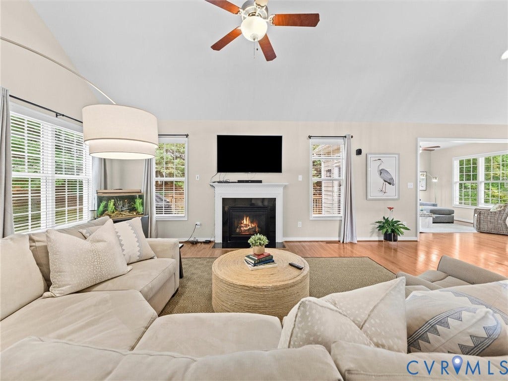 1663 Centerville Parke Lane, The Parke At Centerville, Manakin Sabot, VA 23103 Vaulted ceiling with a ceiling fan, a fireplace with a dark surround, multiple windows with blinds, and wood-finish flooring