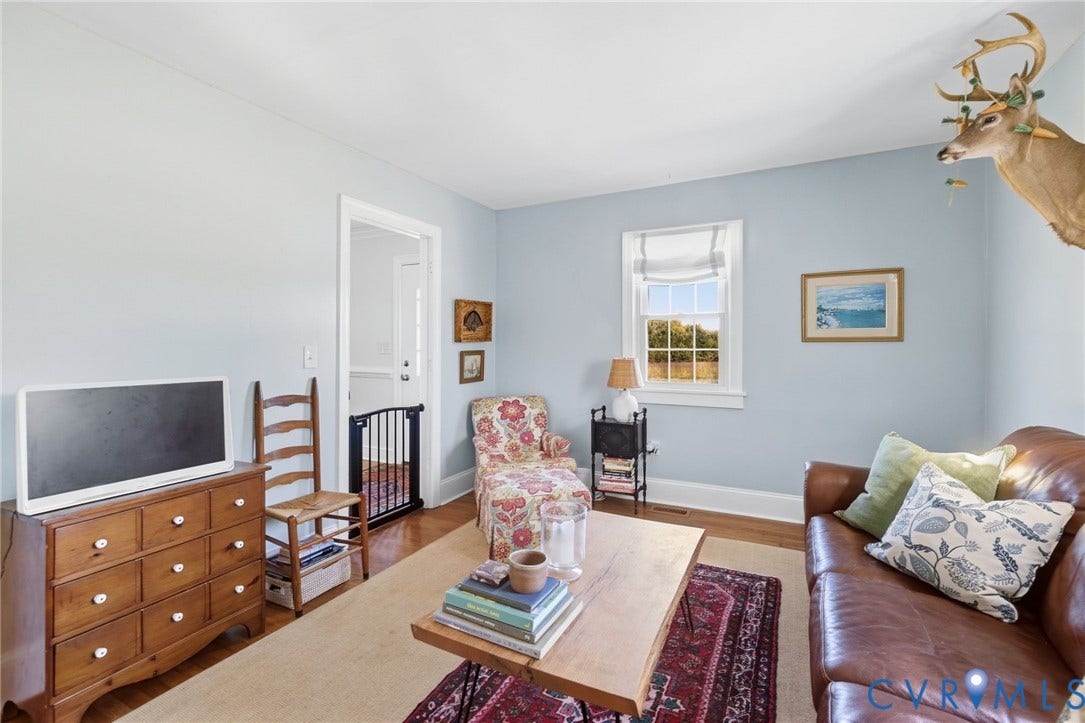 4109 Whitehall Road, Sandy Hook, VA 23153 Hardwood flooring, light blue wall paint, white trim, and a window with natural light