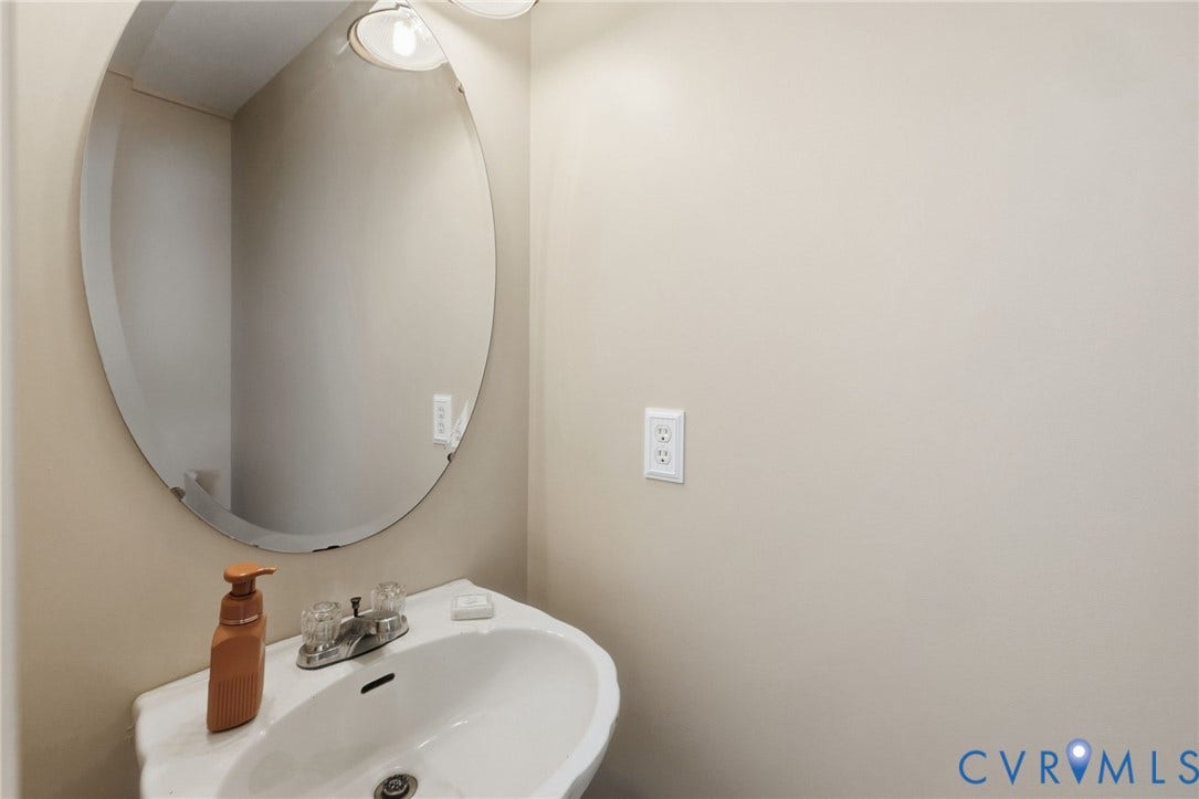 1429 Almondberry Place, Henrico, VA 23231 Wall-mounted pedestal sink with chrome-finish faucet and an oval mirror with integrated lighting