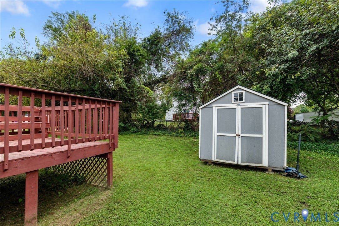1429 Almondberry Place, Henrico, VA 23231 Expansive backyard featuring a manicured lawn, a red wood-finish deck with lattice skirting, a gray storage shed with a white trim, and mature trees