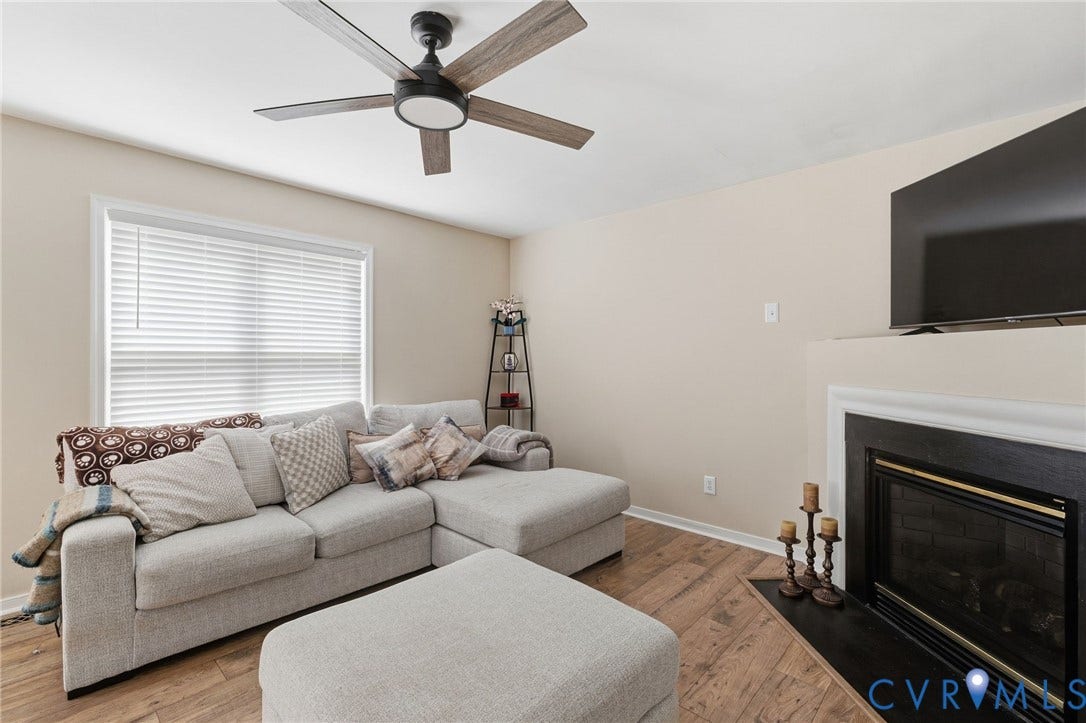 1429 Almondberry Place, Henrico, VA 23231 Wood-finish flooring, white window blinds, ceiling fan with integrated lighting, and a fireplace with a white mantel and black surround
