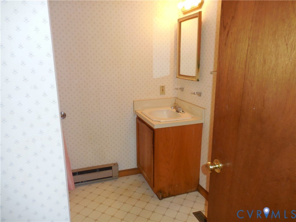 6185 Parrish Road, Louisa, VA 23093 Bathroom featuring a vanity with an integrated sink, wall-mounted mirror, and patterned wallpaper