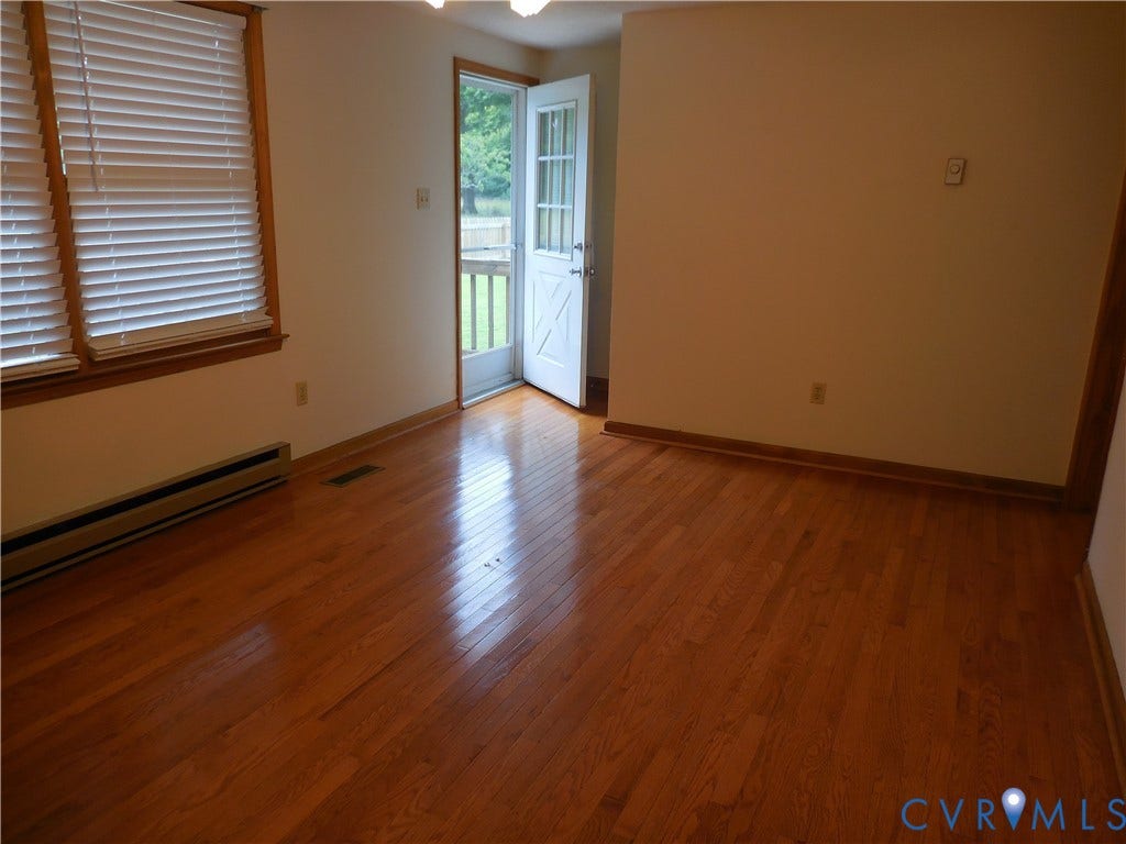 6185 Parrish Road, Louisa, VA 23093 Hardwood flooring, white wall paint, window with blinds, baseboard heating unit, and a glass-paned door