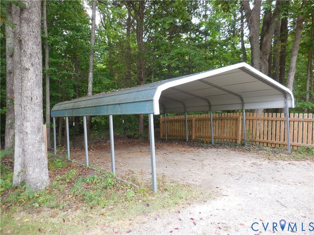 6185 Parrish Road, Louisa, VA 23093 Metal carport structure with a green roof, supported by metal posts, and a wood picket fence