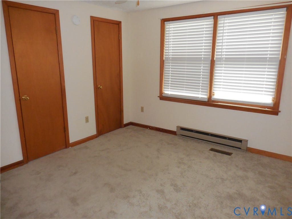 6185 Parrish Road, Louisa, VA 23093 Two wood-finish doors with brass hardware, wood-framed window with blinds, baseboard heating unit, and wall-to-wall carpeting