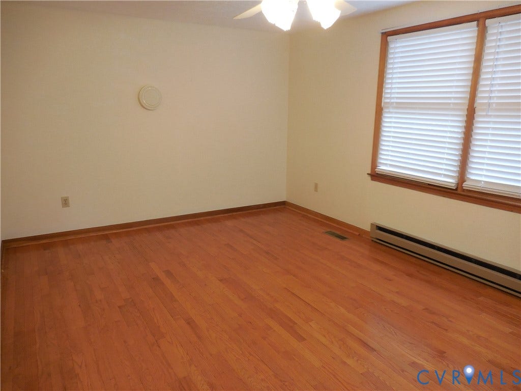 6185 Parrish Road, Louisa, VA 23093 Hardwood flooring, white wall paint, wood-trim windows with blinds, ceiling fan, and baseboard heating