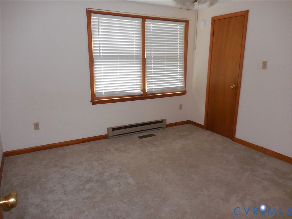 6185 Parrish Road, Louisa, VA 23093 Carpeted flooring, wooden window trim, horizontal blinds, wall-mounted heater, and a wooden door