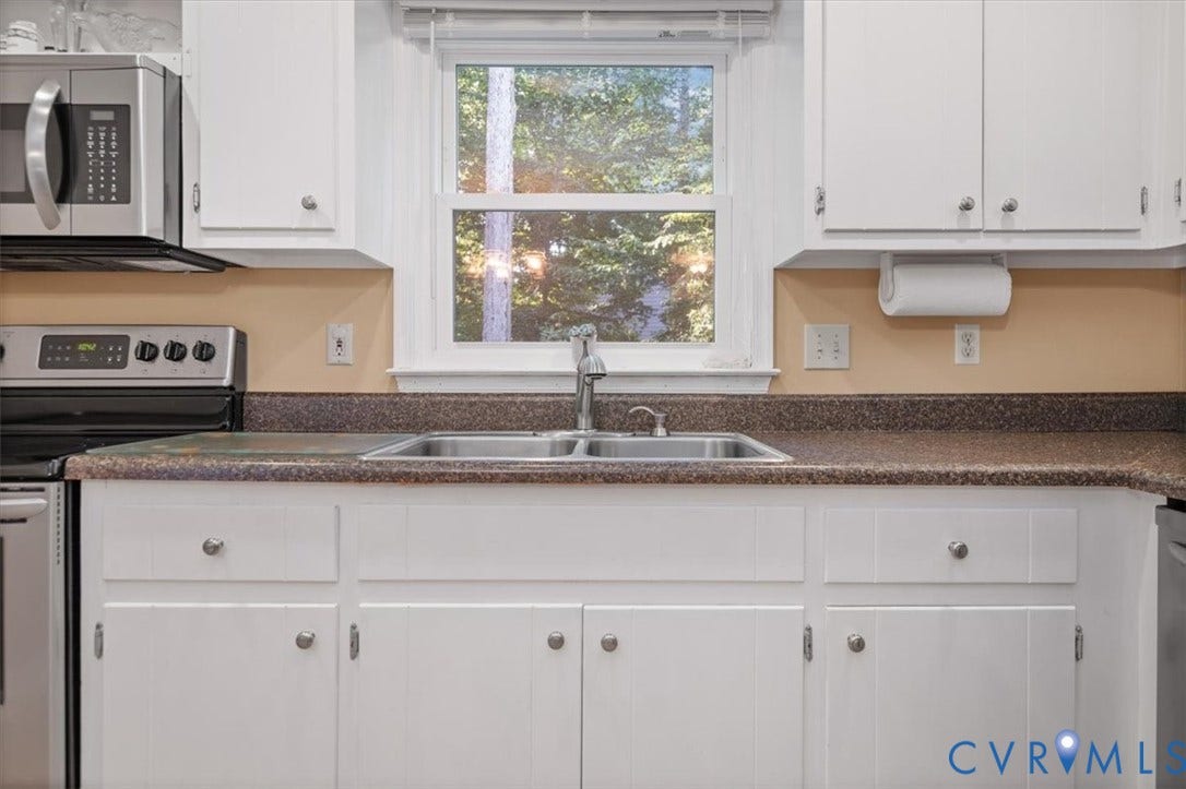 White cabinetry with brushed nickel hardware, stainless steel appliances, dual basin sink, and laminate countertops