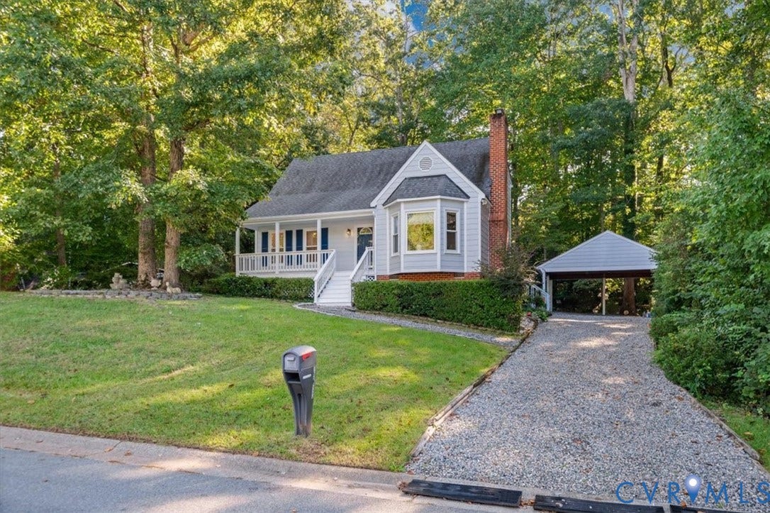 Traditional-style home with light gray siding, white trim, a covered front porch, and a bay window