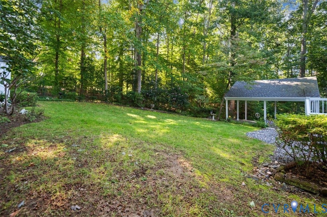 Expansive lawn area, mature trees, gravel pathway, carport structure, and established shrubbery