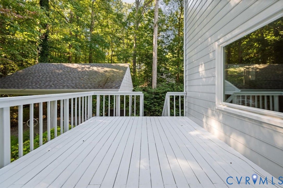 Spacious outdoor deck with a white painted finish, white railing, and exterior wall with horizontal siding