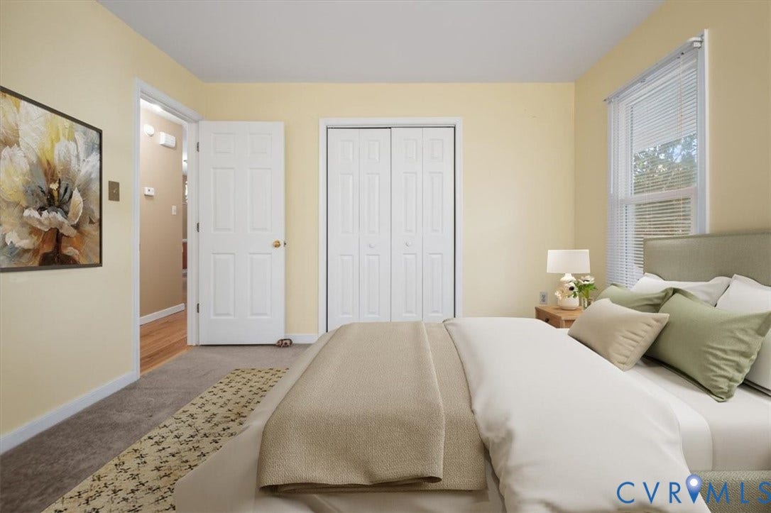 Window with blinds, soft wall color, carpet flooring, bi-fold closet doors, and a paneled interior door