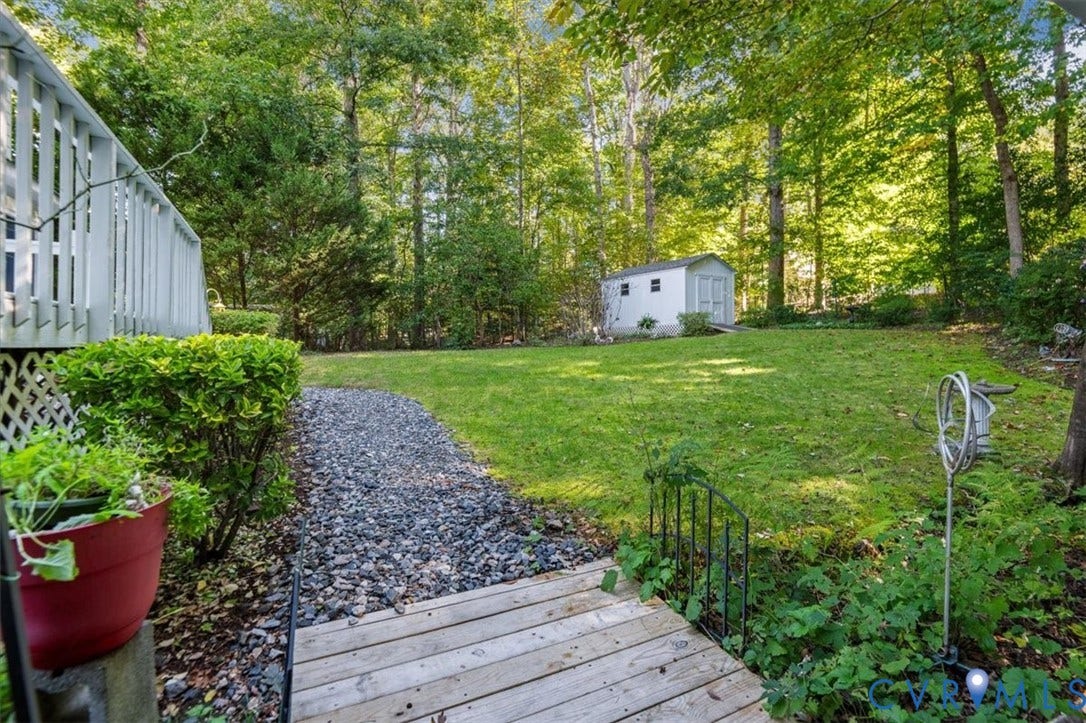 Expansive lawn area, mature trees, gravel pathway, wood planking, and storage shed
