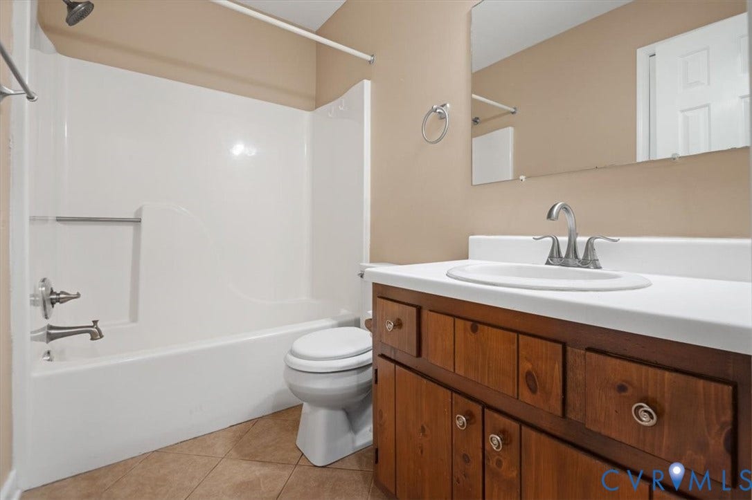Full bathroom featuring a single vanity with wood-finish cabinetry, a white countertop, and a white integrated sink