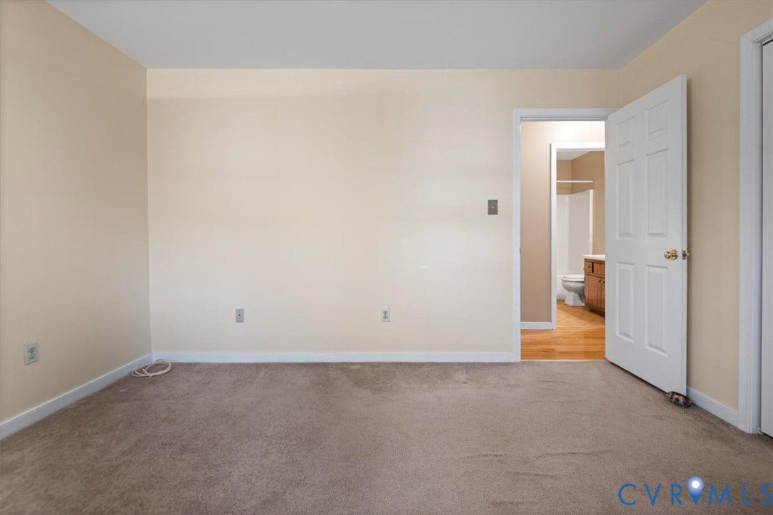 Carpeted flooring, neutral wall color, white trim, access to a bathroom, wood-finish flooring in the bathroom