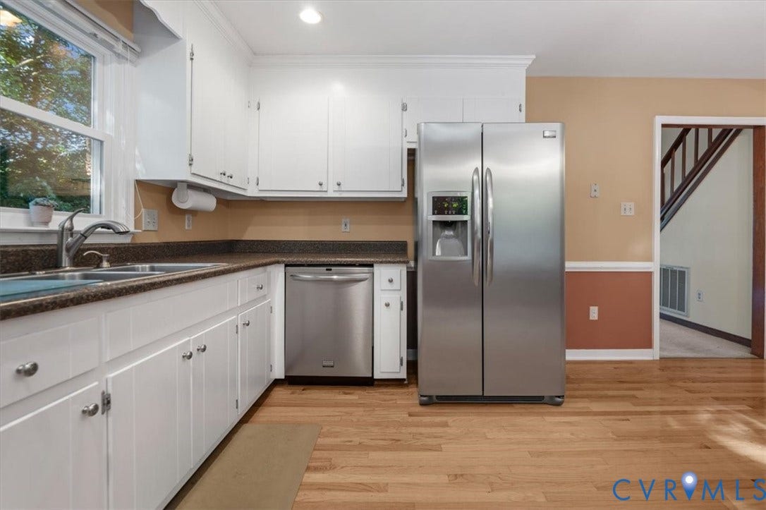 Kitchen featuring white cabinetry, wood-finish flooring, stainless steel appliances, and a double basin sink