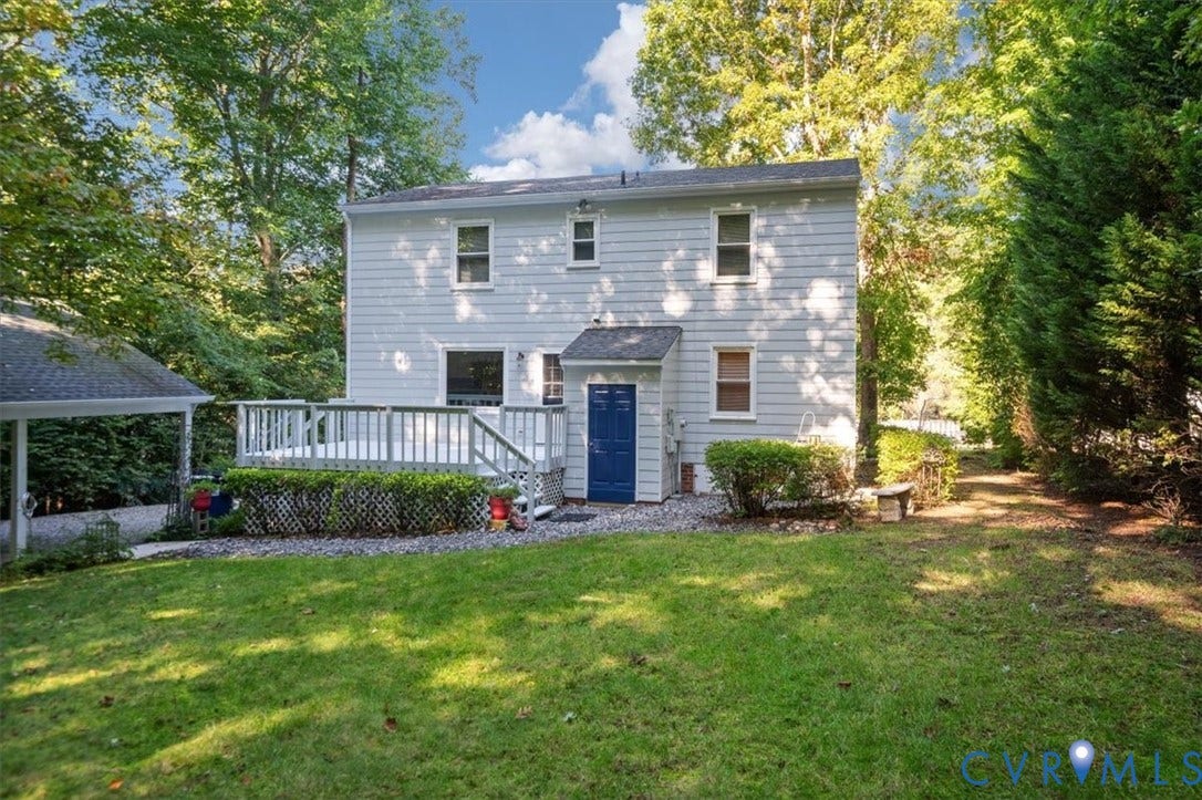 Expansive backyard featuring a manicured lawn, a multi-level deck, and mature perimeter trees