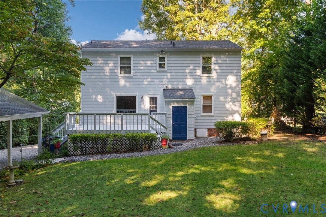 Exterior featuring light blue siding, a multi-level deck, a blue painted door, and a detached carport