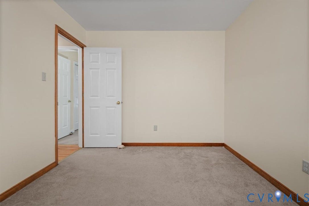 Neutral wall paint, carpeting, wood-finish trim, and a paneled interior door
