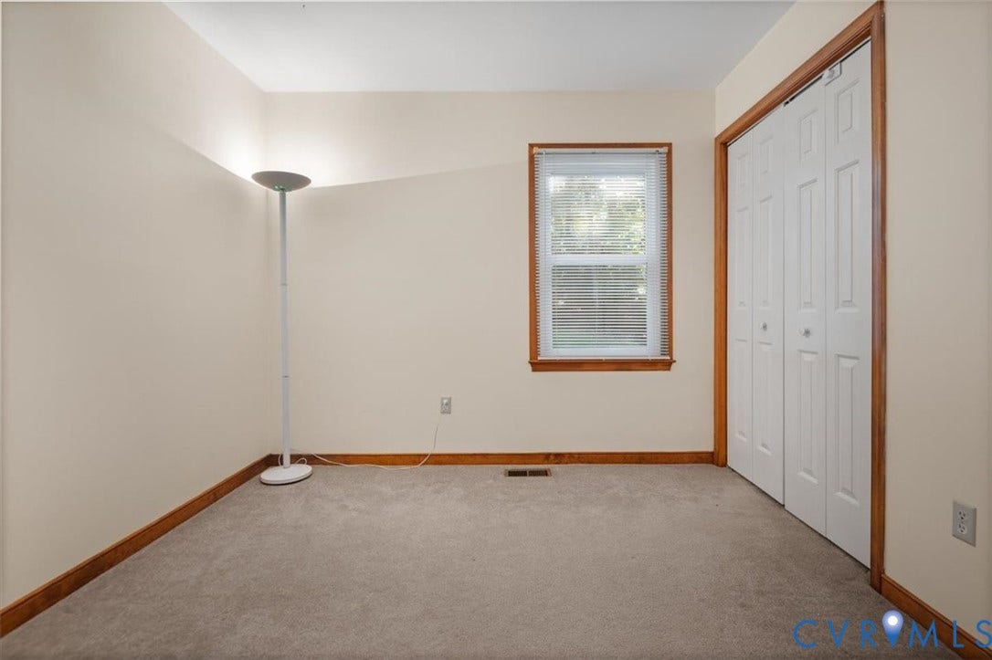 Wall-to-wall carpeting, wood-finish trim, window with blinds, and bi-fold closet doors
