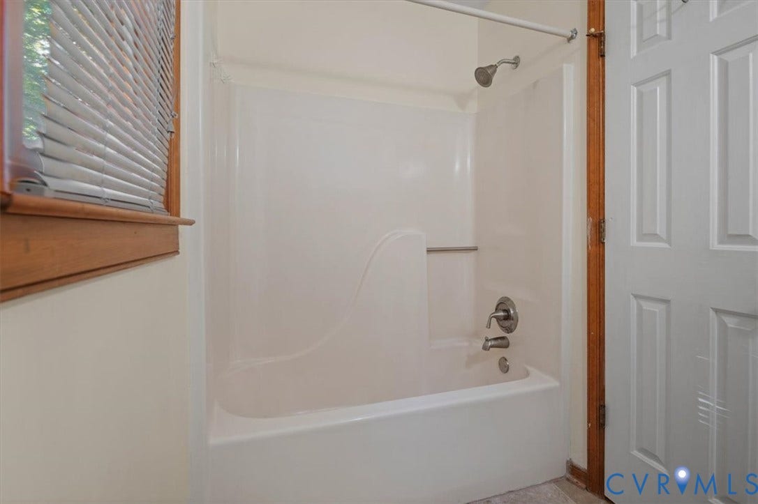 White tub and shower combination with a curved wall, brushed nickel fixtures, and a white paneled door