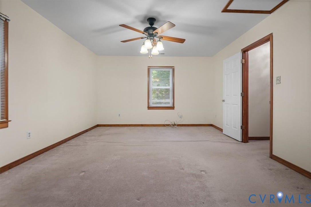 Neutral wall paint, carpet flooring, ceiling fan, natural light window, and wood-finish trim