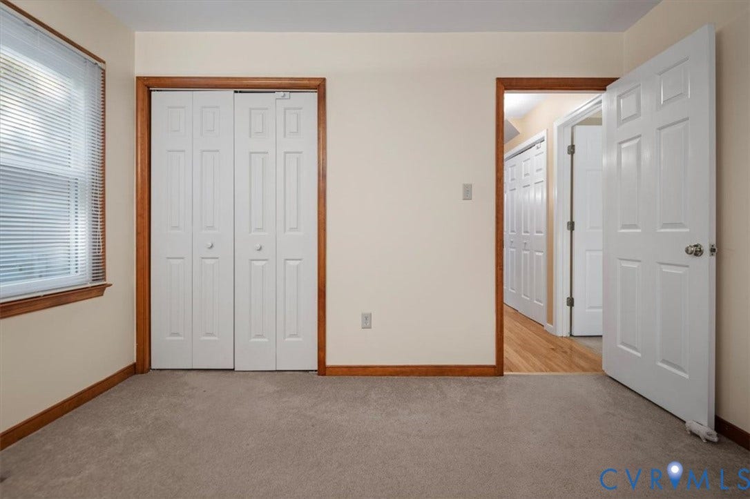 Neutral wall paint, wood trim, bi-fold closet doors, paneled interior doors, and carpet flooring
