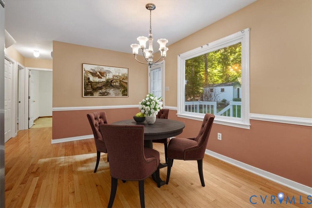 Hardwood flooring, chandelier lighting, chair rail molding, and a large window
