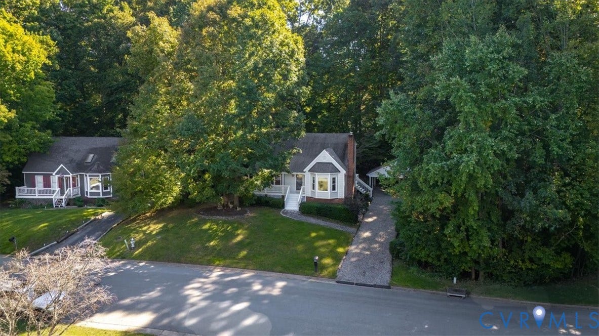 Traditional-style home featuring a prominent bay window, brick chimney, and a paved driveway