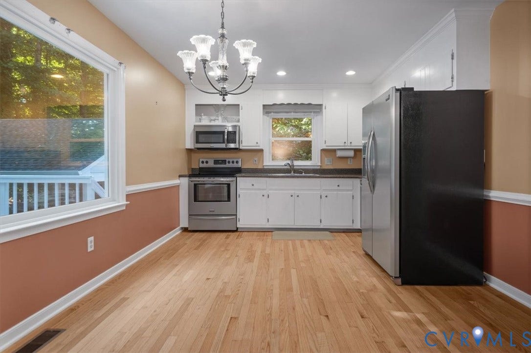 Wood-finish flooring, stainless steel appliances, white cabinetry, recessed lighting, and a decorative chandelier