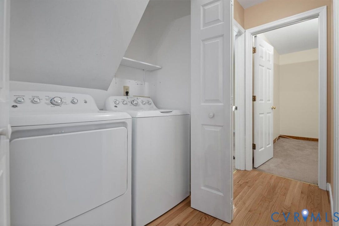 Laundry area with built-in shelving, hardwood-finish flooring, and panel doors