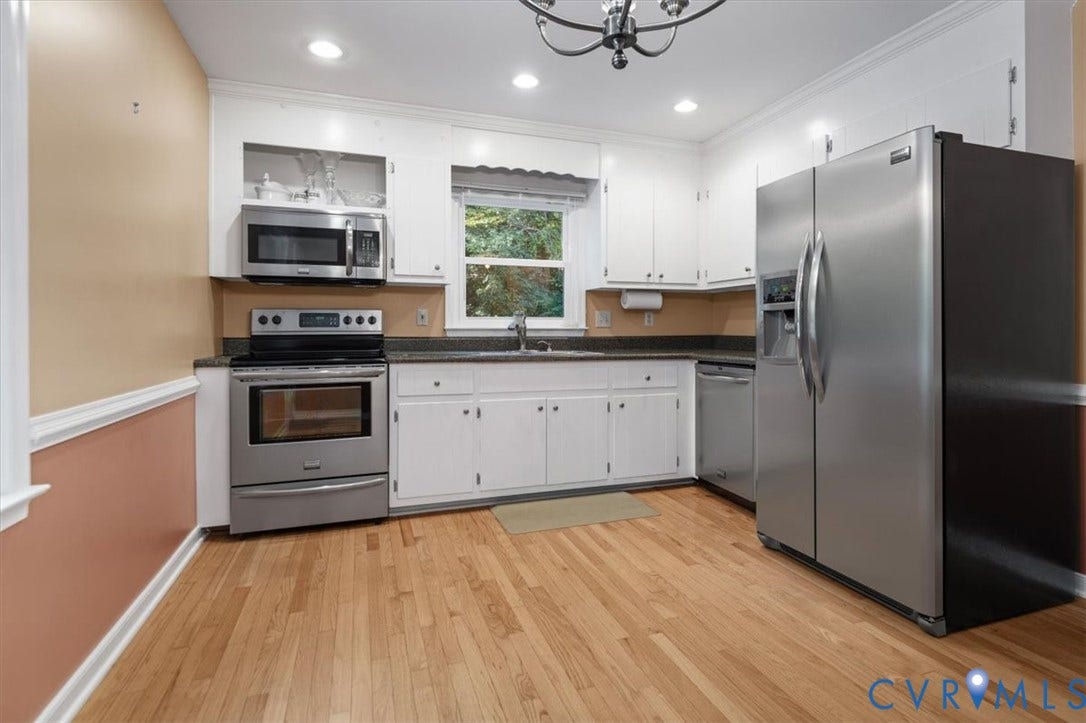 Hardwood flooring, stainless steel appliances, white cabinetry, dark countertops, and recessed lighting