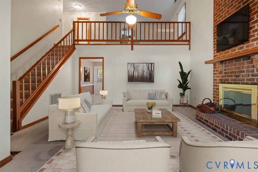Two-story living area featuring a brick fireplace with a wood mantle, a natural wood staircase, and an upper-level balcony