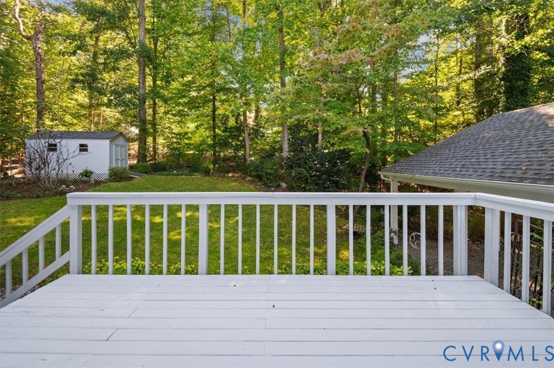 Spacious outdoor deck with white railing overlooking a verdant backyard
