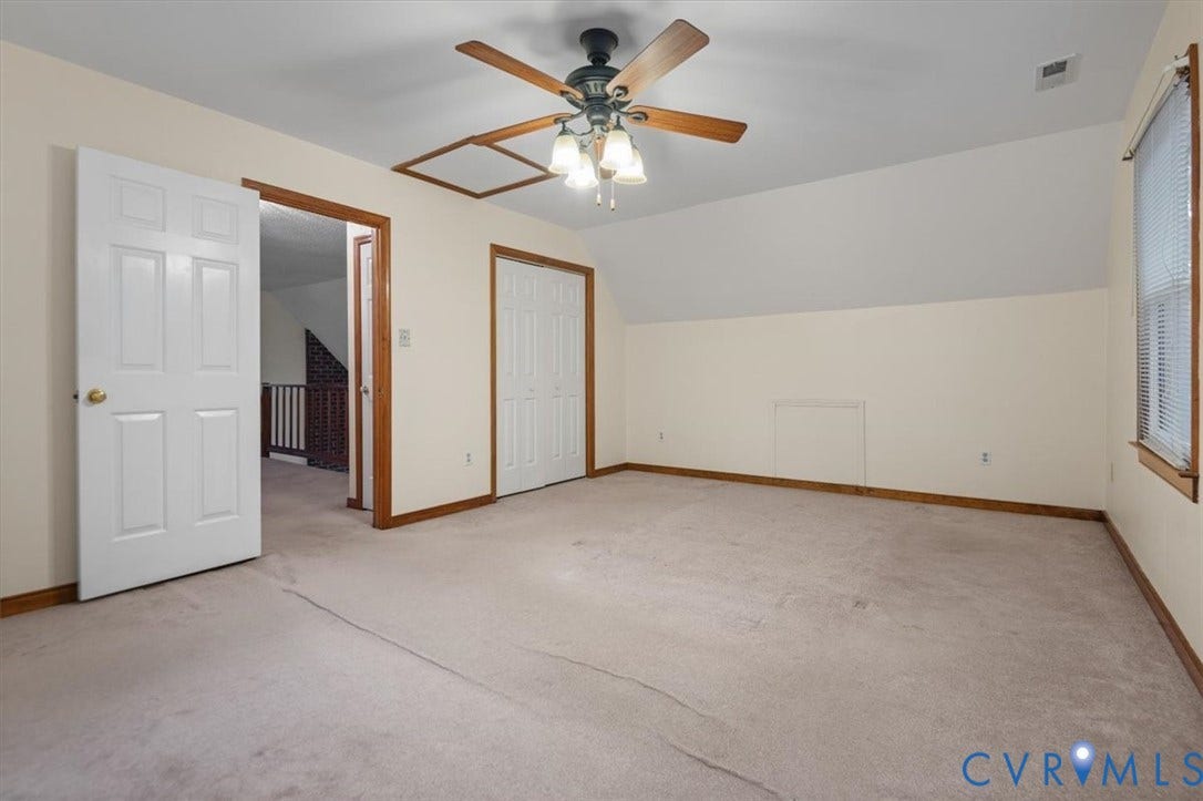 Spacious room with sloped ceiling, light-toned carpeting, and a ceiling fan with integrated lighting