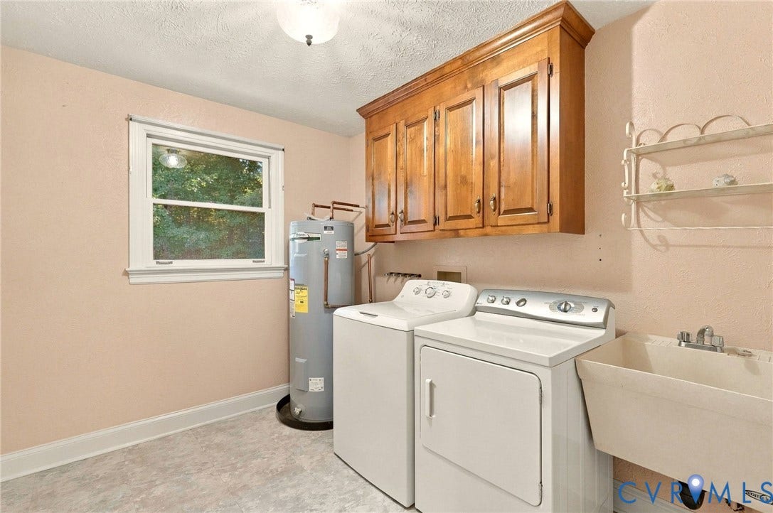 Laundry area with overhead wood cabinetry, single window, utility sink, and light-colored flooring
