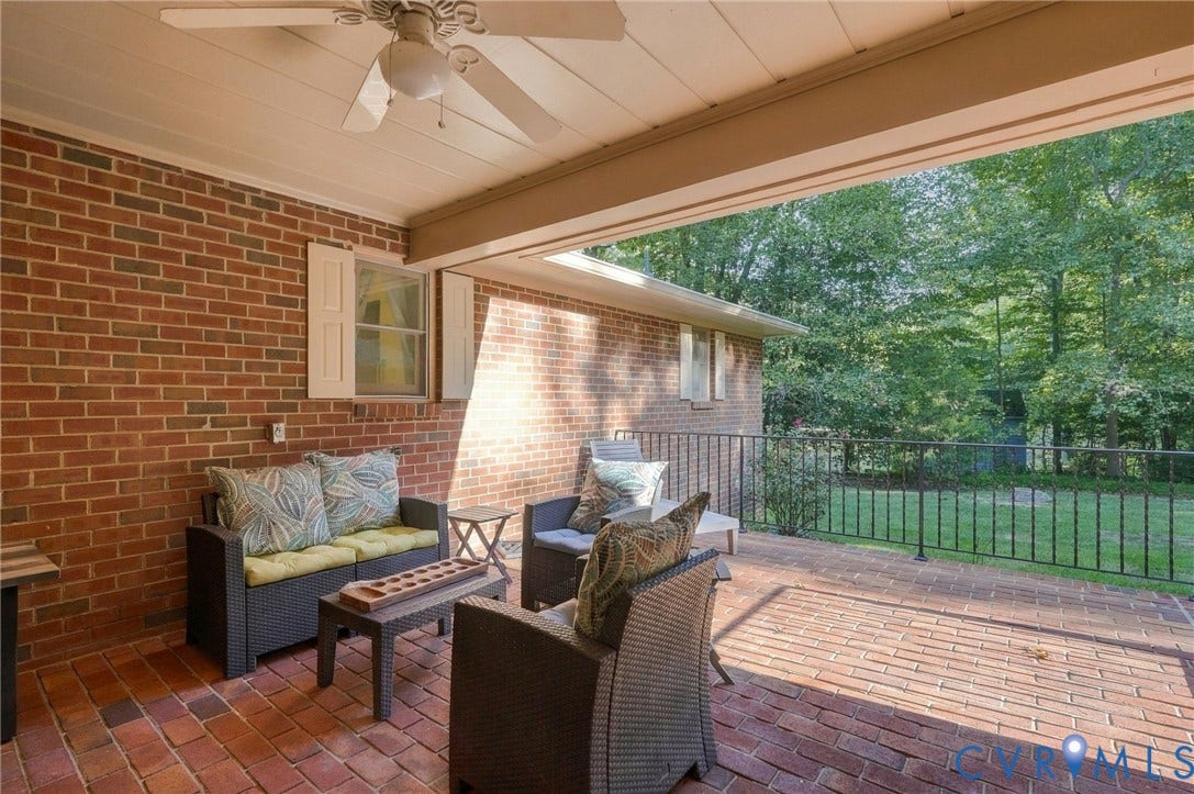 Brick patio with an overhead ceiling fan, covered porch, and black iron railing
